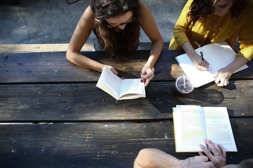 Three people reading and writing at a table.
