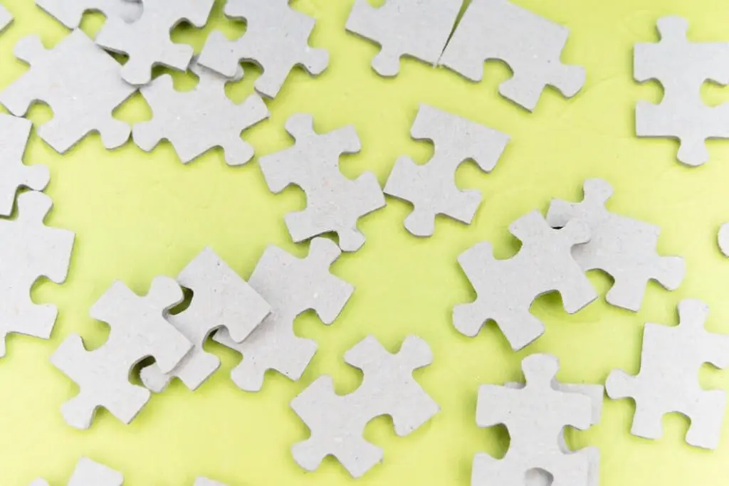 Scattered white puzzle pieces on green background.