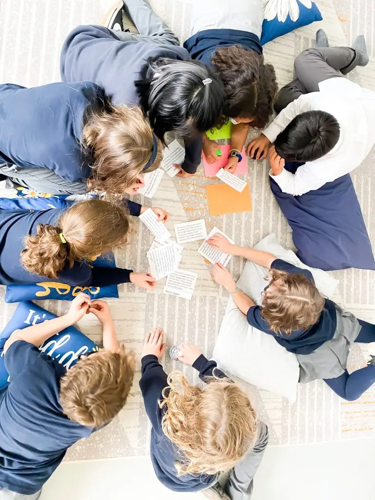 Children in group activity with papers on floor.