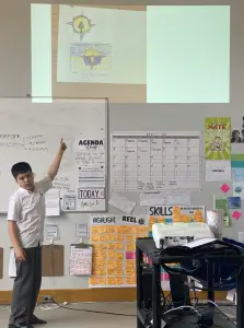 Student presenting in classroom with Ukraine drawing.