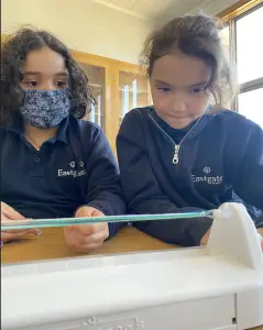 Two children using a sewing machine.