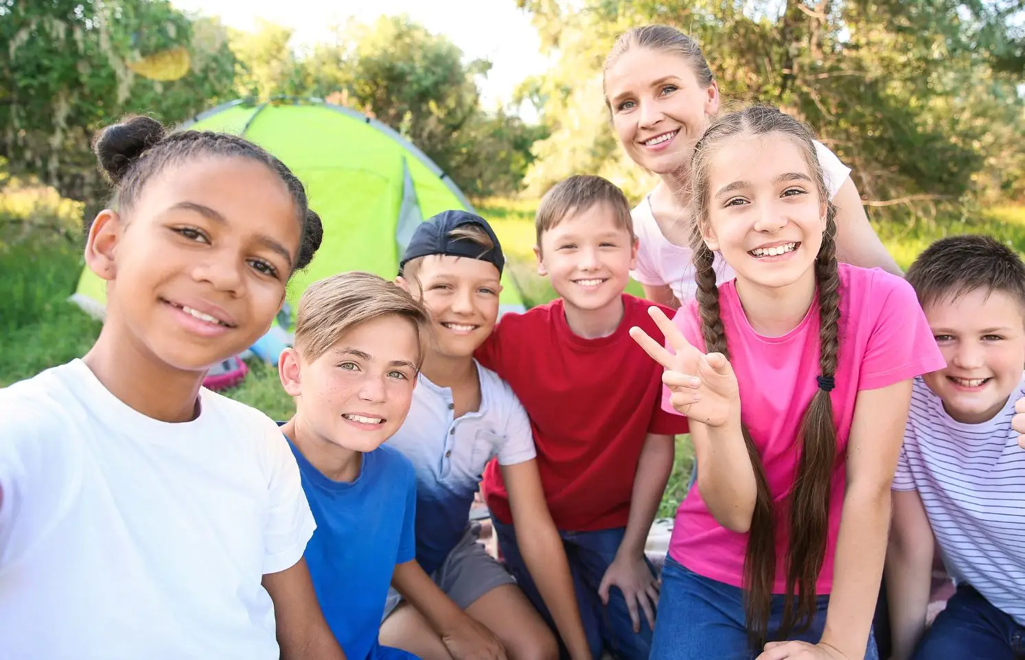 Group of kids camping, smiling at camera